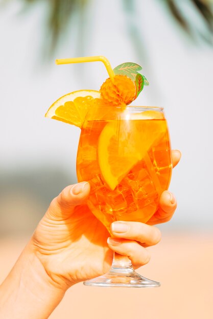 Vaso decorado de refresco de naranja en la mano.