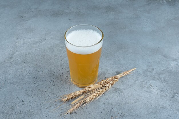 Foto gratuita un vaso de deliciosa cerveza y trigo sobre fondo gris. foto de alta calidad