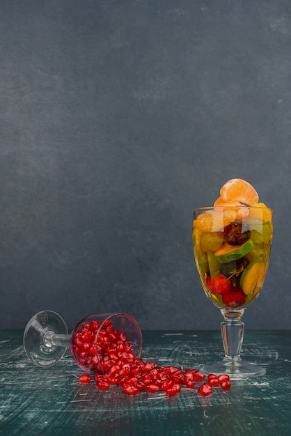 Foto gratuita vaso de frutas mixtas y semillas de granada sobre mesa de mármol.