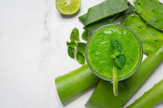 Vaso de jugo de aloe vera en piso blanco