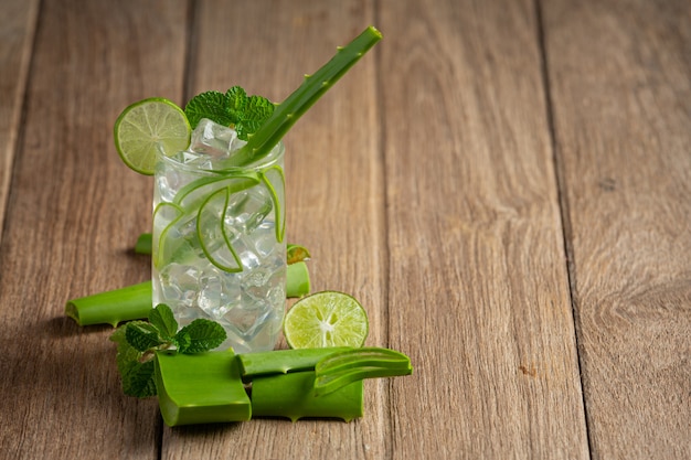 Vaso de jugo de aloe vera puesto sobre un piso de madera