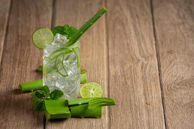 Vaso de jugo de aloe vera puesto sobre un piso de madera