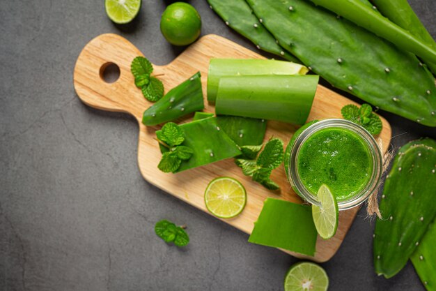 Vaso de jugo de aloe vera puesto sobre una tabla de cortar de madera