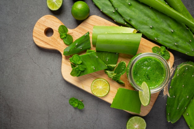 Vaso de jugo de aloe vera puesto sobre una tabla de cortar de madera