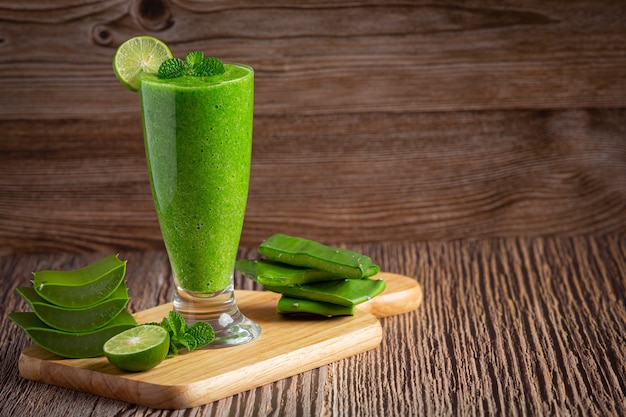 Vaso de jugo de aloe vera puesto sobre una tabla de cortar de madera