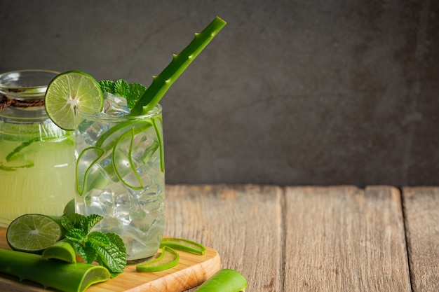 Vaso de jugo de aloe vera puesto sobre una tabla de cortar de madera