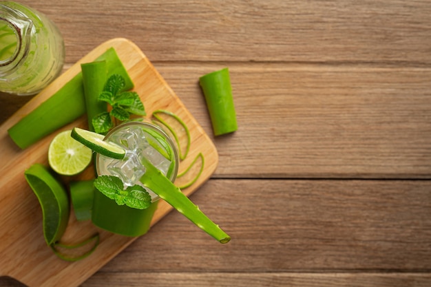 Vaso de jugo de aloe vera puesto sobre una tabla de cortar de madera