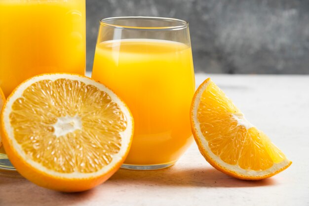 Un vaso de jugo fresco con rodajas de naranja.