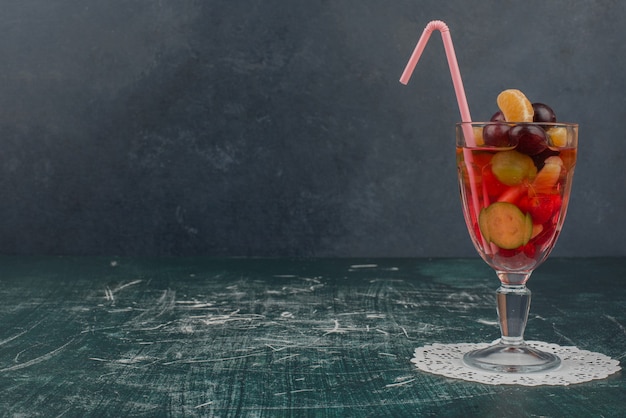 Vaso de jugo de frutas mixtas sobre mesa de mármol.