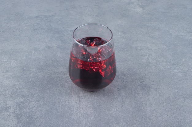 Un vaso de jugo de granada fresco con cubitos de hielo. Foto de alta calidad