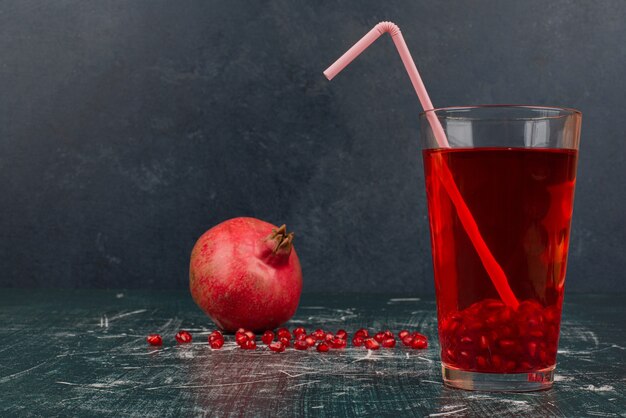 Vaso de jugo y granada en mesa de mármol