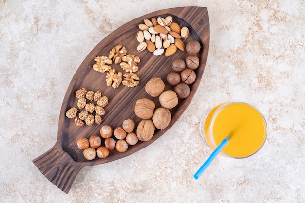 Un vaso de jugo junto a una bandeja con nueces variadas y bolas de chocolate.