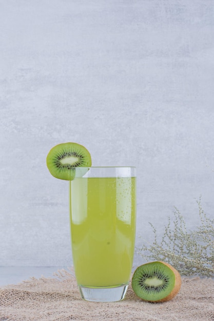 Un vaso de jugo de kiwi fresco sobre arpillera. Foto de alta calidad