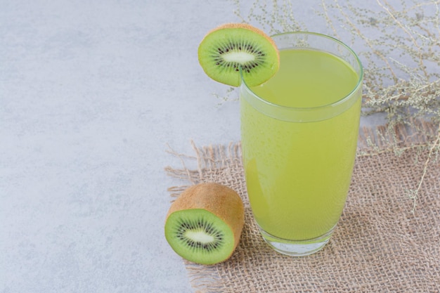 Un vaso de jugo de kiwi fresco sobre arpillera. Foto de alta calidad