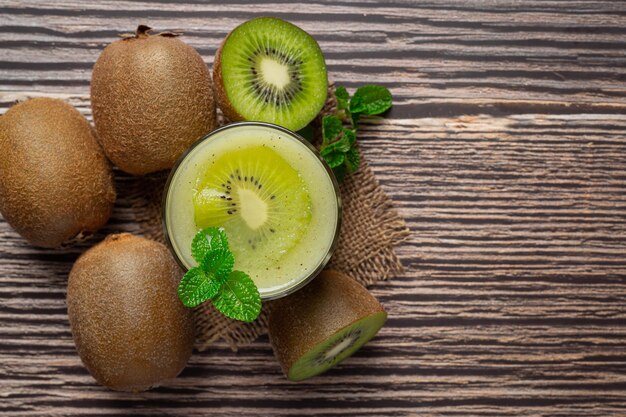 Vaso de jugo de kiwi puesto sobre un piso de madera