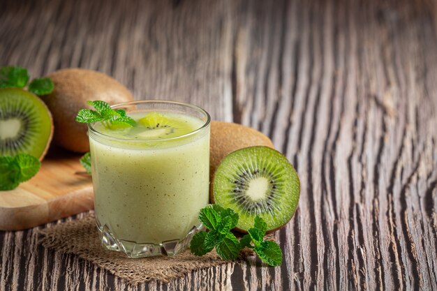 Vaso de jugo de kiwi puesto sobre un piso de madera