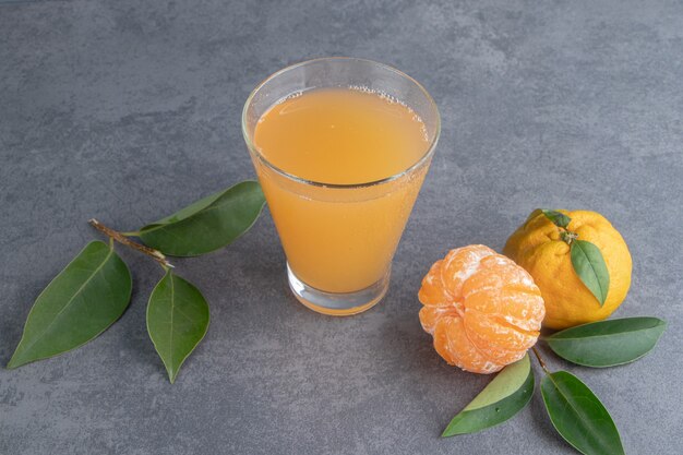 Un vaso de jugo de mandarina con hojas.