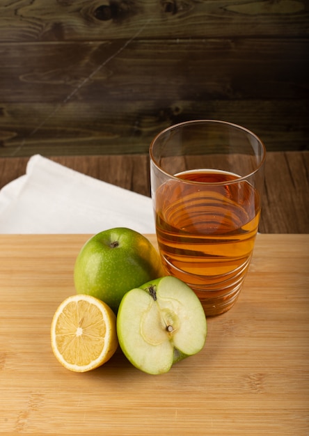 Un vaso de jugo de manzana y limón sobre una tabla de madera