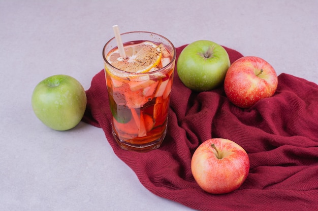 Foto gratuita un vaso de jugo con manzanas en toalla roja
