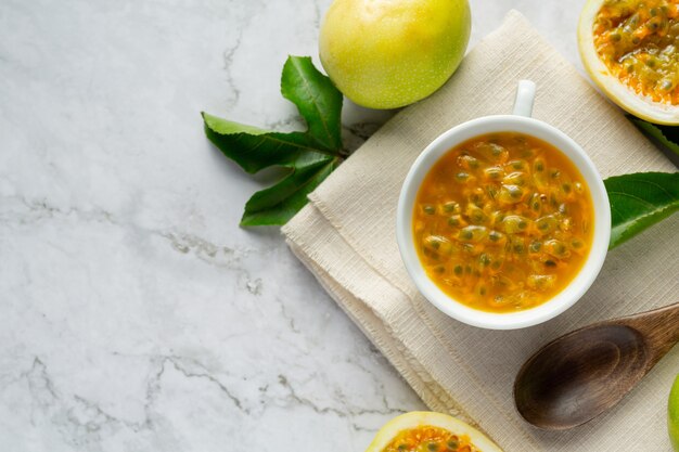 un vaso de jugo de maracuyá y fruta de la pasión fresca cortada a la mitad en tela blanca