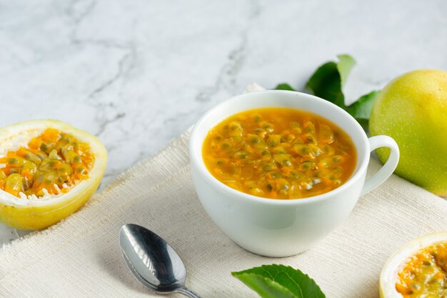 un vaso de jugo de maracuyá y fruta de la pasión fresca cortada a la mitad en tela blanca