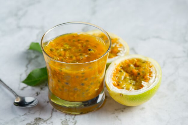 Un vaso de jugo de maracuyá en un piso de mármol blanco.