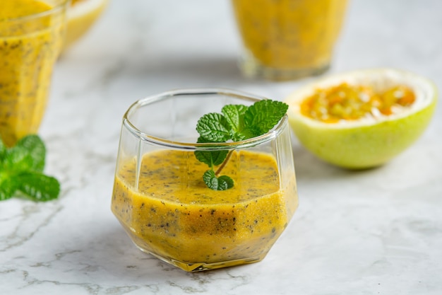 Un vaso de jugo de maracuyá en un piso de mármol blanco.