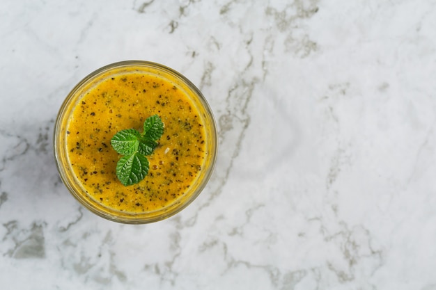 Un vaso de jugo de maracuyá en un piso de mármol blanco.