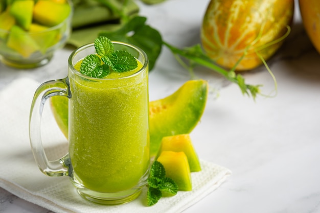 Vaso de jugo de melón puesto sobre piso de mármol blanco