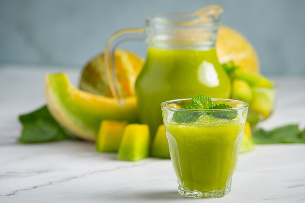 Vaso de jugo de melón puesto sobre piso de mármol blanco