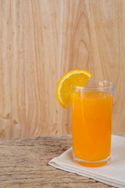 Vaso de jugo de naranja colocado en la madera.