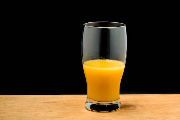 Vaso de jugo de naranja en escritorio de madera