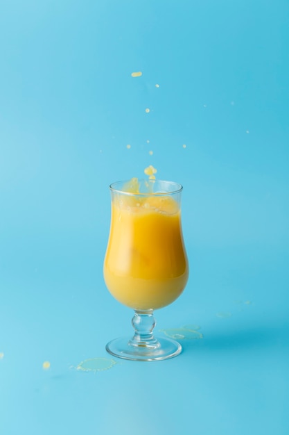 Foto gratuita vaso de jugo de naranja y fondo azul