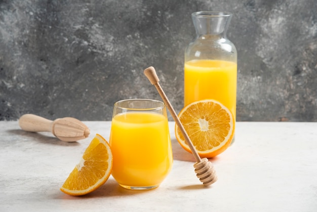 Un vaso de jugo de naranja fresco con un cucharón de madera.
