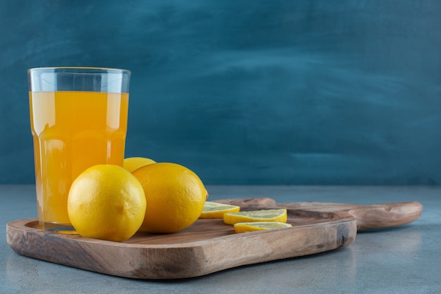 Un vaso de jugo de naranja con limones frescos.