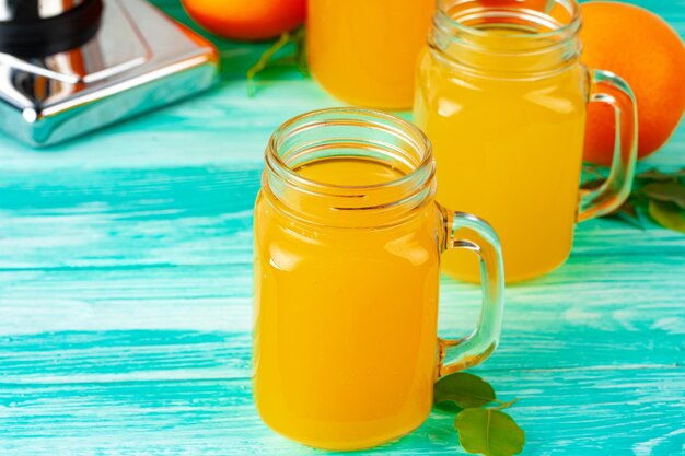 Vaso con jugo de naranja en la mesa de madera verde