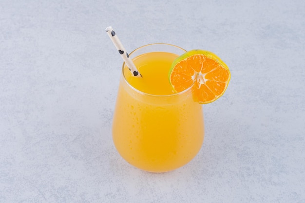 Un vaso de jugo de naranja con paja sobre fondo de piedra. Foto de alta calidad