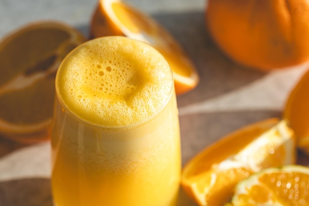 Vaso de jugo de naranja en primer plano sobre un fondo borroso con naranjas