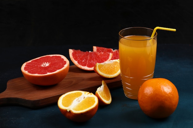 Un vaso de jugo de naranja con rodajas de naranja y pomelo.