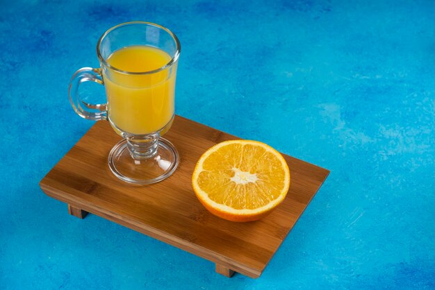 Un vaso de jugo de naranja sobre tabla de madera.