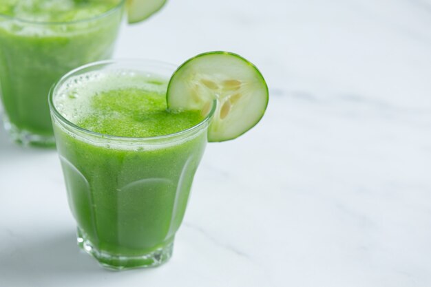 Vaso de jugo de pepino fresco sobre fondo de mármol