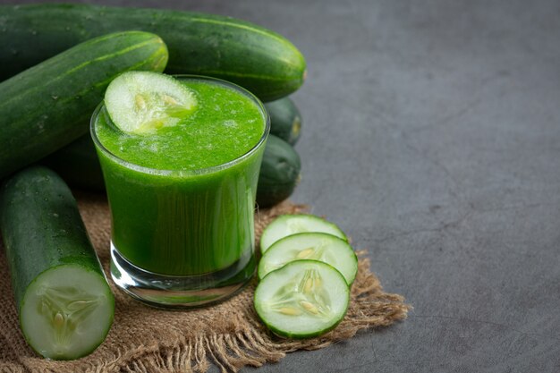 Vaso de jugo de pepino fresco sobre fondo oscuro