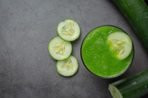 Vaso de jugo de pepino fresco sobre fondo oscuro