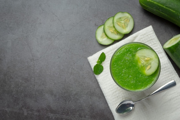 Vaso de jugo de pepino fresco sobre fondo oscuro