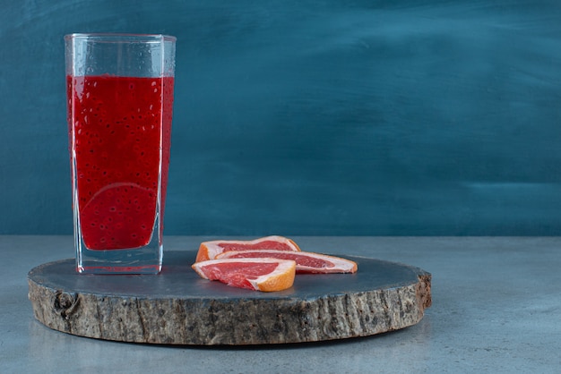Un vaso de jugo rojo con rodajas de pomelo.