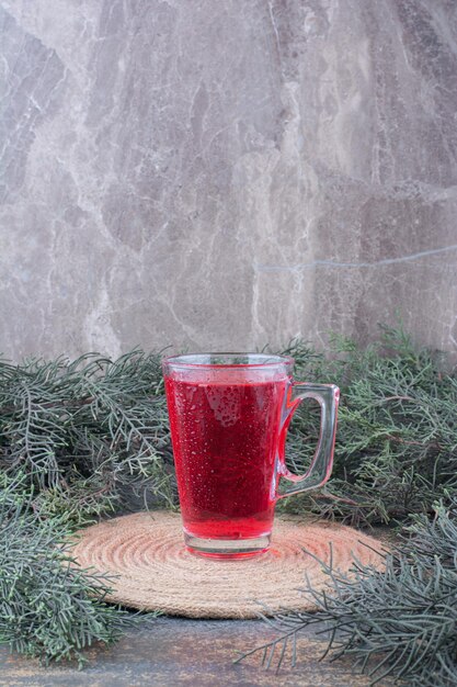 Un vaso de jugo rojo sobre mármol.