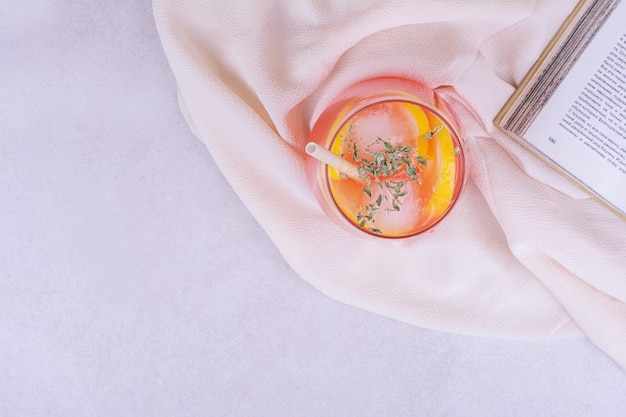 Un vaso de jugo en la superficie blanca con limones