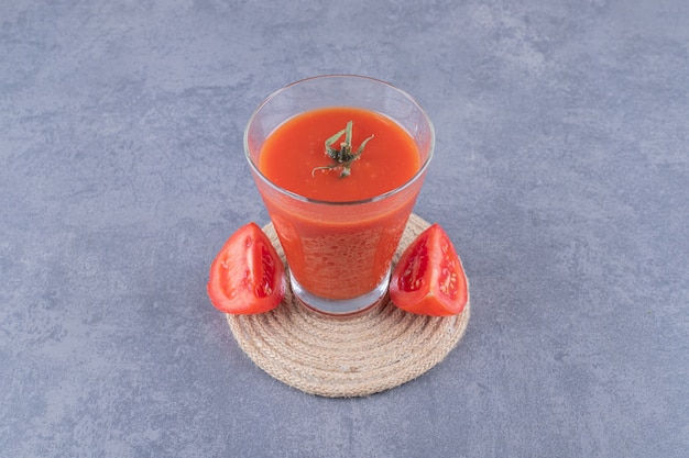 Vaso de jugo de tomate fresco y tomates en una tabla de madera.