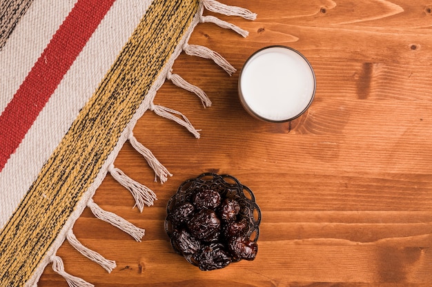 Foto gratuita vaso de leche cerca de platillo con ciruelas dulces y tapete