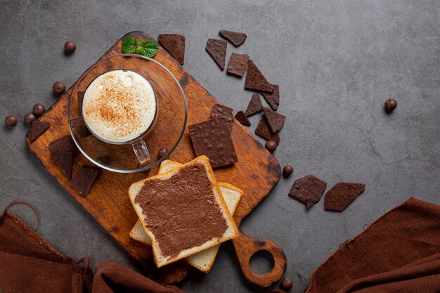 Vaso de leche con chocolate en la superficie oscura.